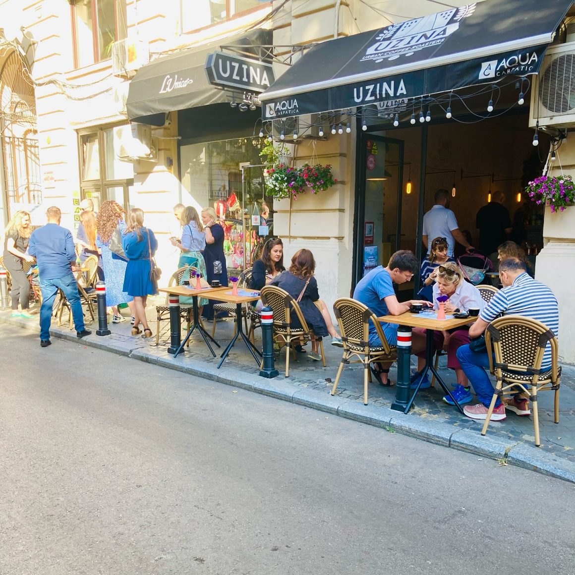 mai multi oameni la mese pe trotoarul de la Uzina Coffee. Restaurante Amzei