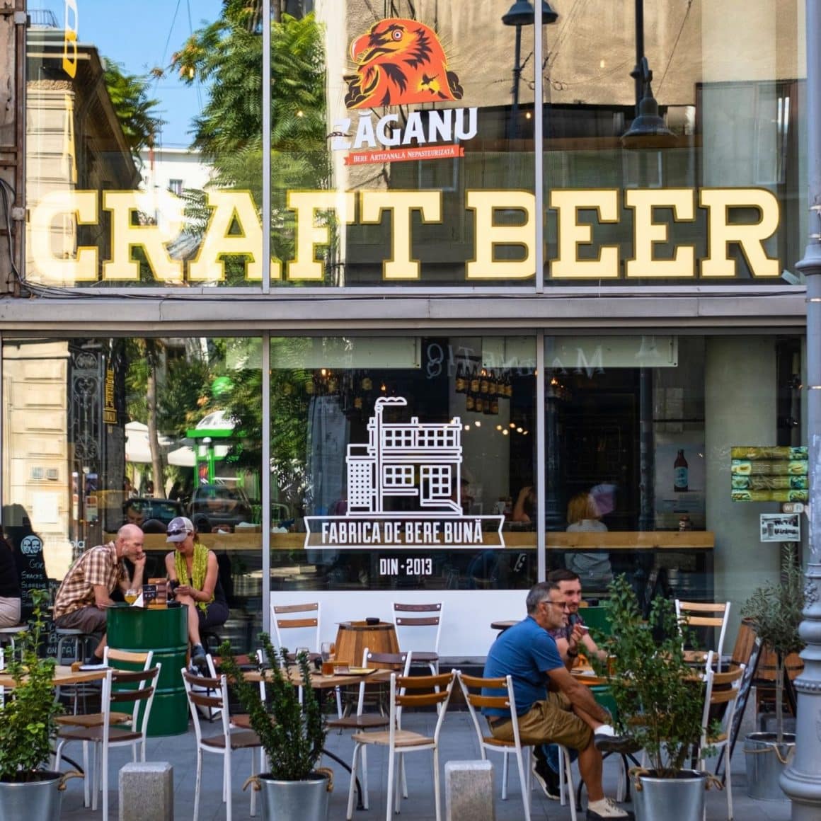 cativa oameni beau bere la mese pe terasa de pe trotura din fata la Zaganu Bistro & Craft Beer Bar București