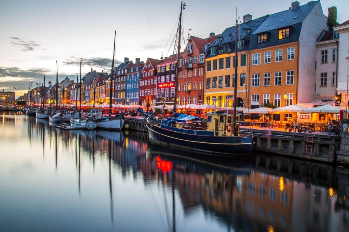 Panorama asupra orașului Copenhaga, fotografiat toamna, cu cladiri colorate si canalul cu barci andocate. Cele mai frumoase destinații de toamnă, capitale europene pentru city break. Ce să vizitezi și unde să mănânci.