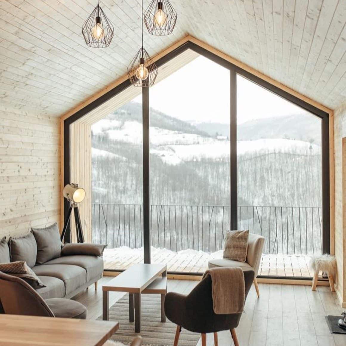 cabana in stil scandinav, mobilata minimalist, cu geamuri mari prin care se vad dealurile si copacii acoperiti de zapada. Cabana Berg. Pensiuni cu ciubăr