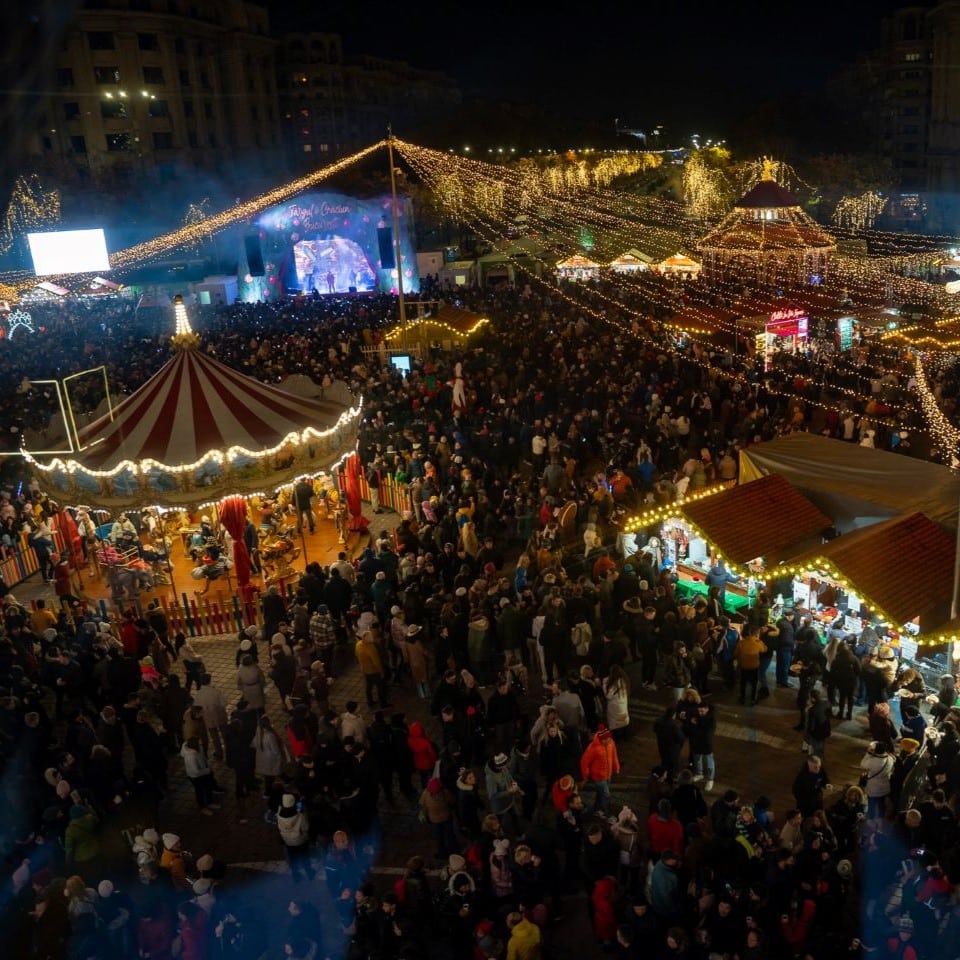 imagine de ansamblu, fotografiata de sus, noaptea, la Targul de Crăciun din Piața Constituției, București, cu brad impodobit, carusel si luminite aprinse. Târguri de Crăciun București 2024