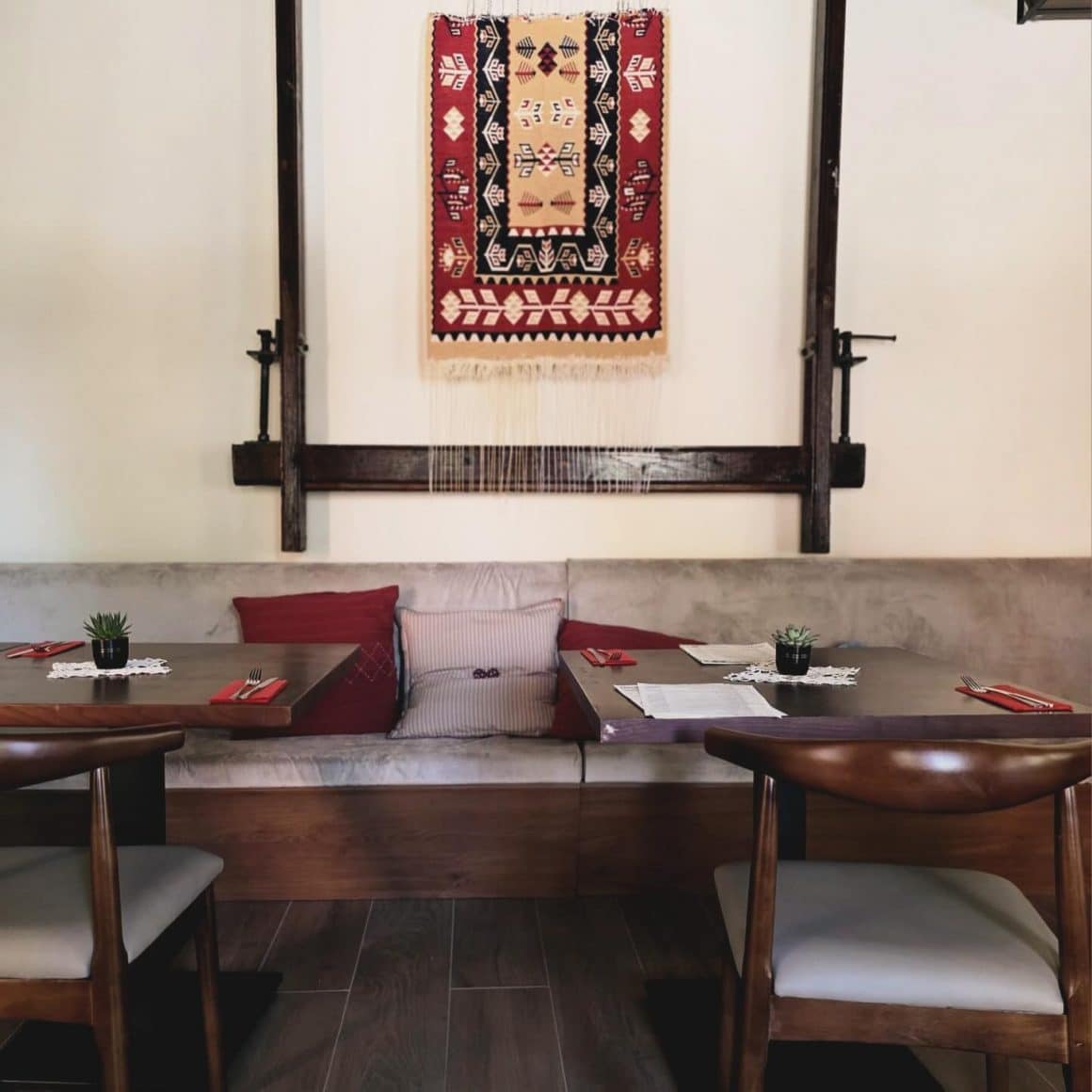 mese de lemn asezate in dreptul unui gherghef decorativ, pe perete la Strubun restaurant