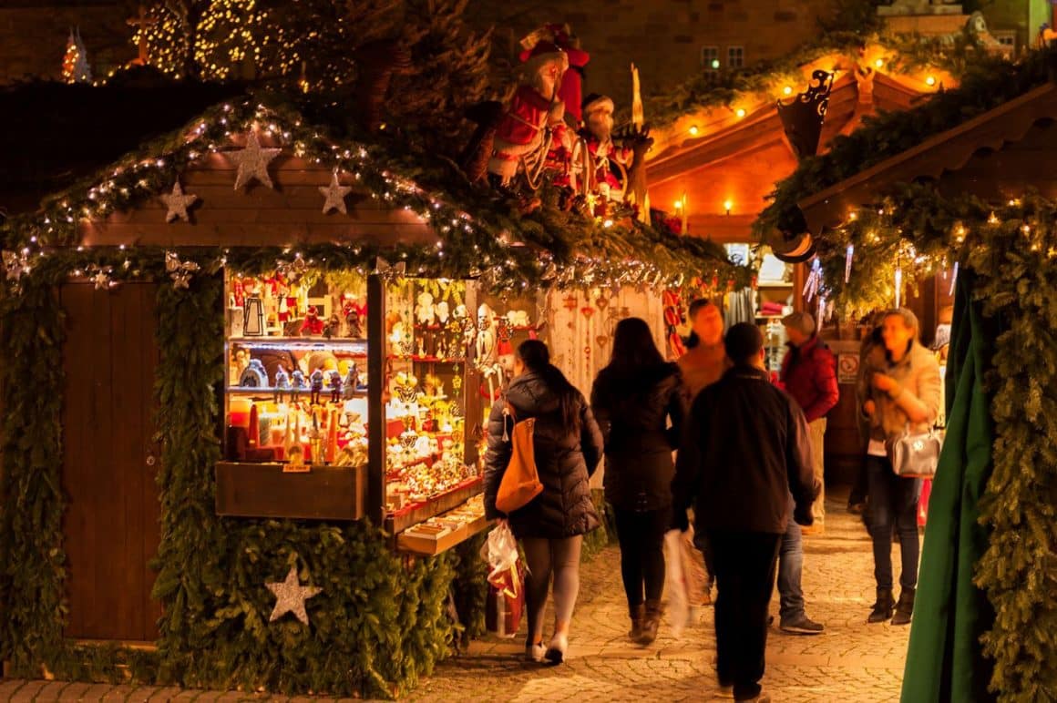 casute de la târgul de Crăciun Laminor Winter Wonderland, fotografiate seara, cu lumini aprinse si oameni care se plimbă printre ele. Târguri de Crăciun București 2024