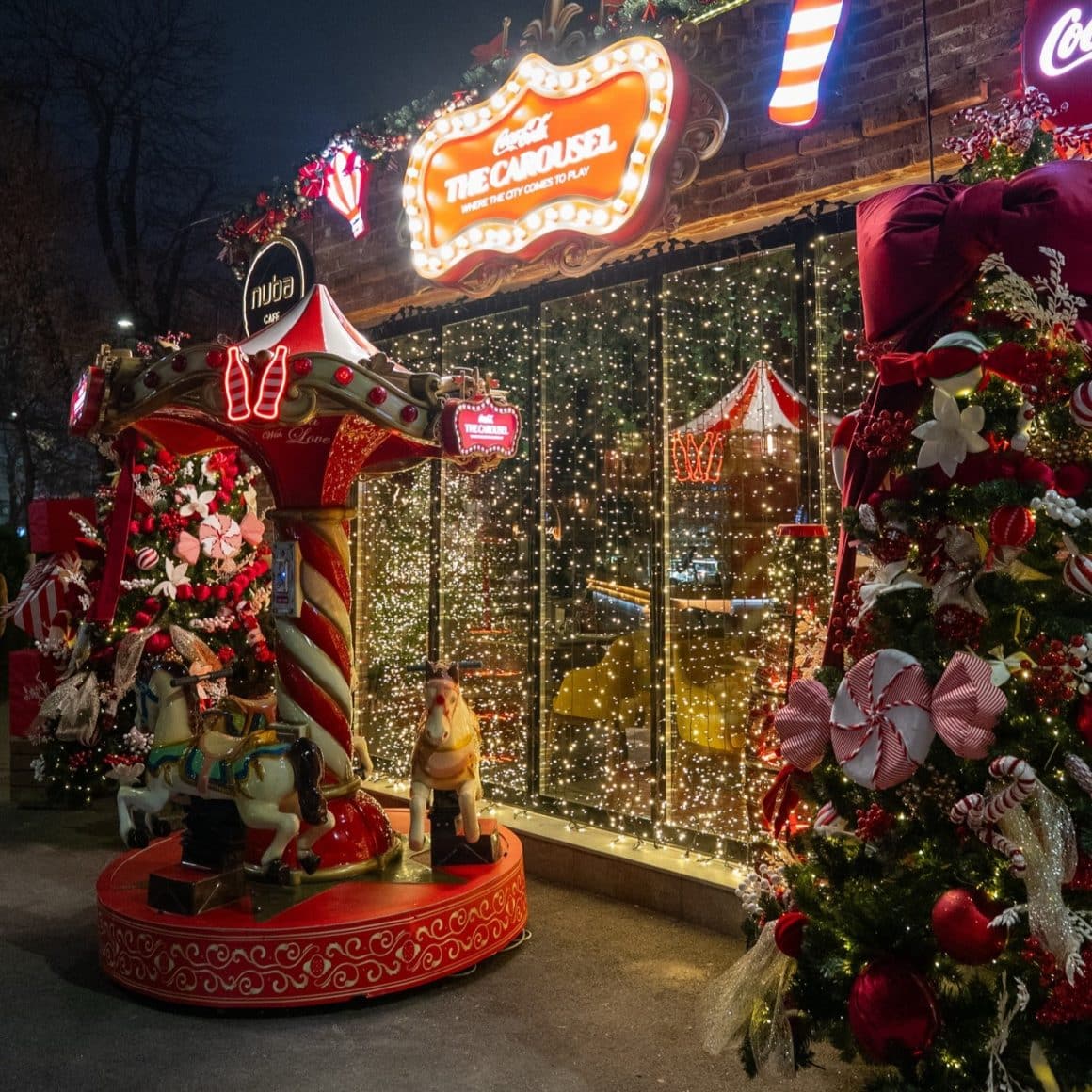 vitrina de la Nuba Cafe impodobita cu luminite, in fata careia se afla un carusel de craciun si un brad impodobit