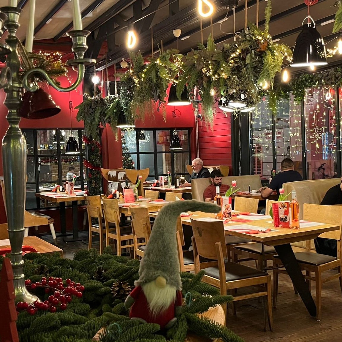 Mai multi oameni iau cina in restaurantul decorat festiv de la Red Angus. Cele mai frumos decorate locații de Crăciun din București.