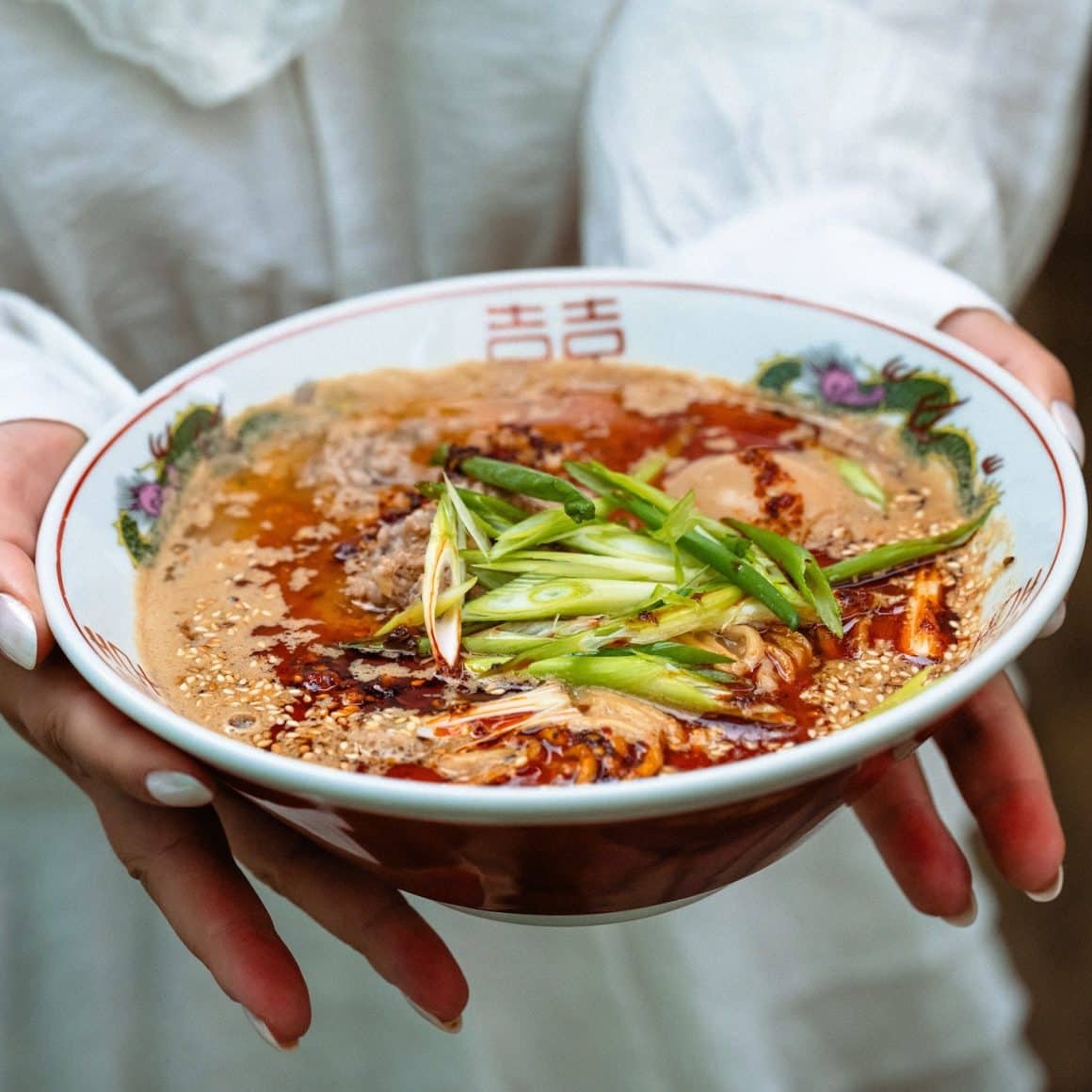 Bol de ramen Barukan servit la Bistro Lanka, cu supă cremoasă, ulei chili, ceapă verde și tăiței proaspeți, fotografiat de aproape.