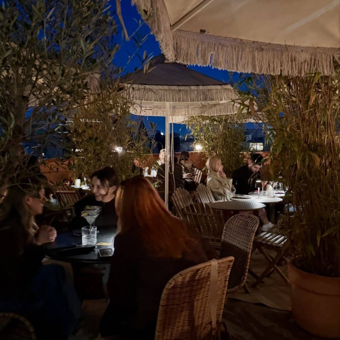 Mai multi oameni seata, la terasa, vara, la restaurant Condesa București cu terasa de tip rooftop