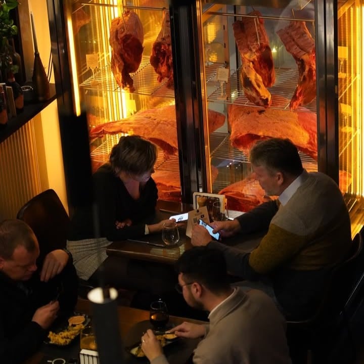 cuplu matur ia cina in dreptul unei vitrine cu steak-uri la NOA Steakhouse
