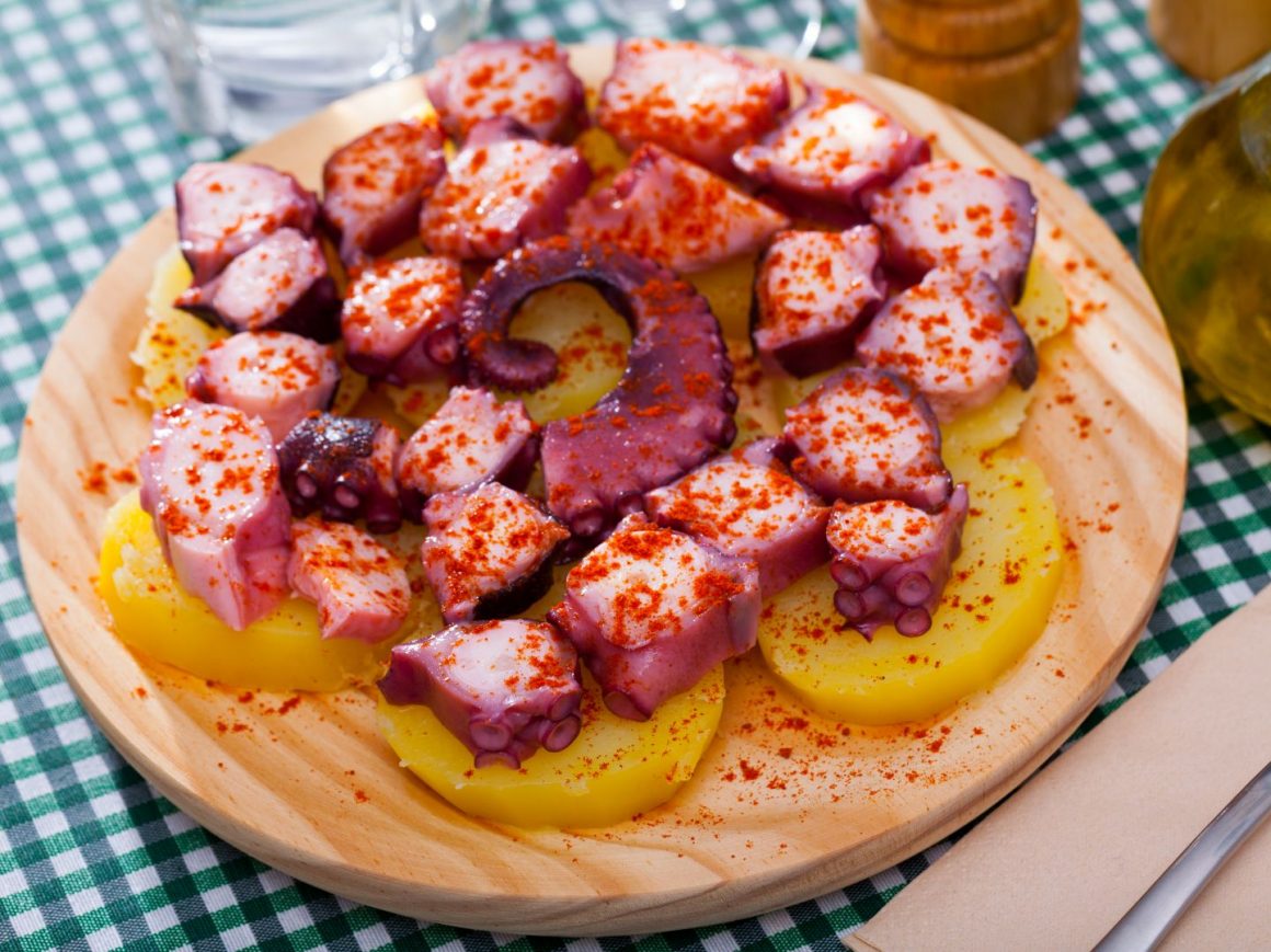 close up cu pulpo a la gallega, bucati de caracatita cu boia, asezate in farfurie impreuna cu felii groase de cartof, ceva ce să mănânci în Spania.