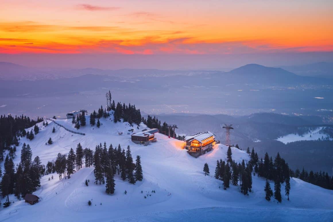 vedere de sus asupra partiei principale din Poaiana Brașov, cu oameni care schiază, si brazii plini de zăpada, stațiune unde să faci Revelionul la munte