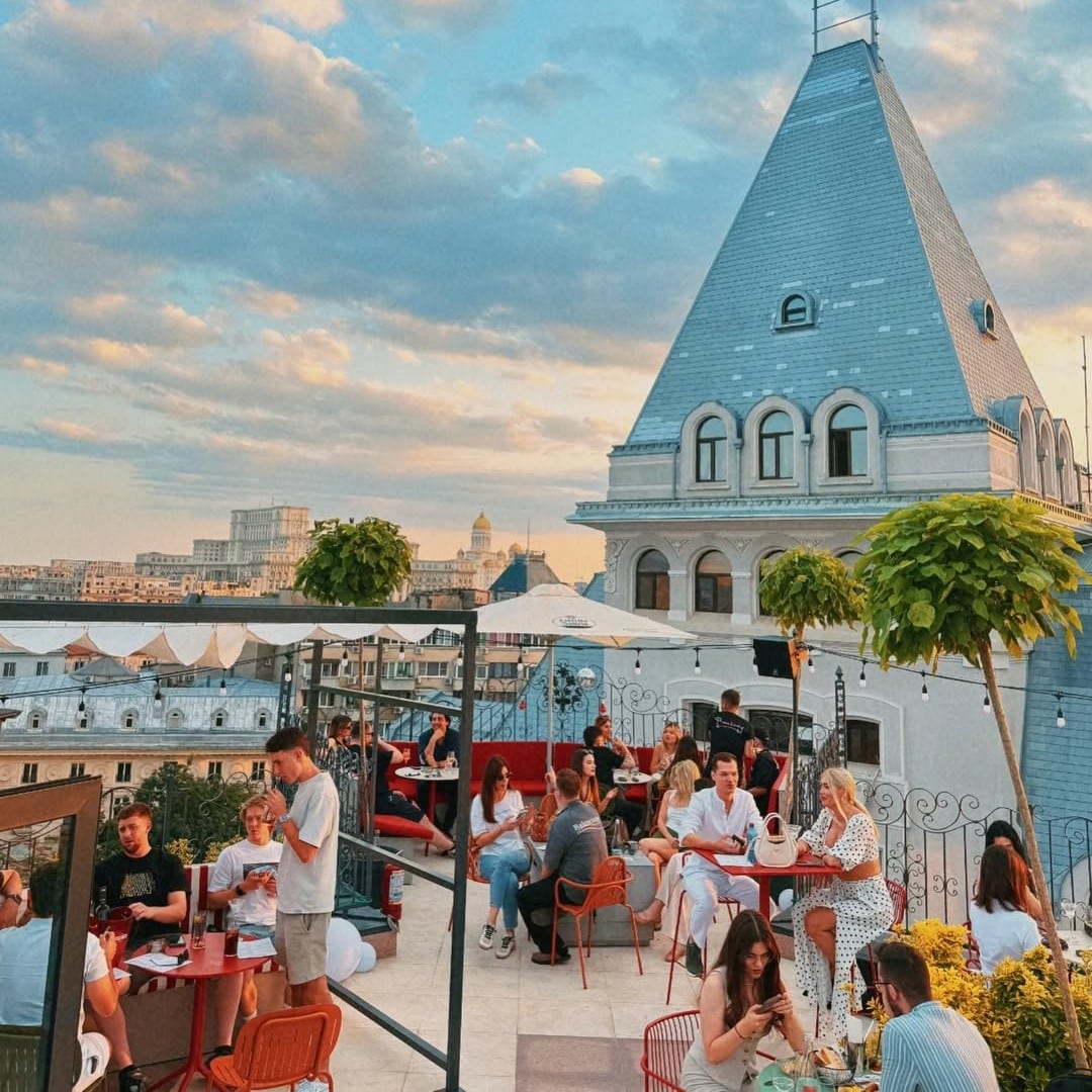 mai mulți oameni la mese pe terasa la Bartini rooftop București. Unde ieșim de 1 Mai