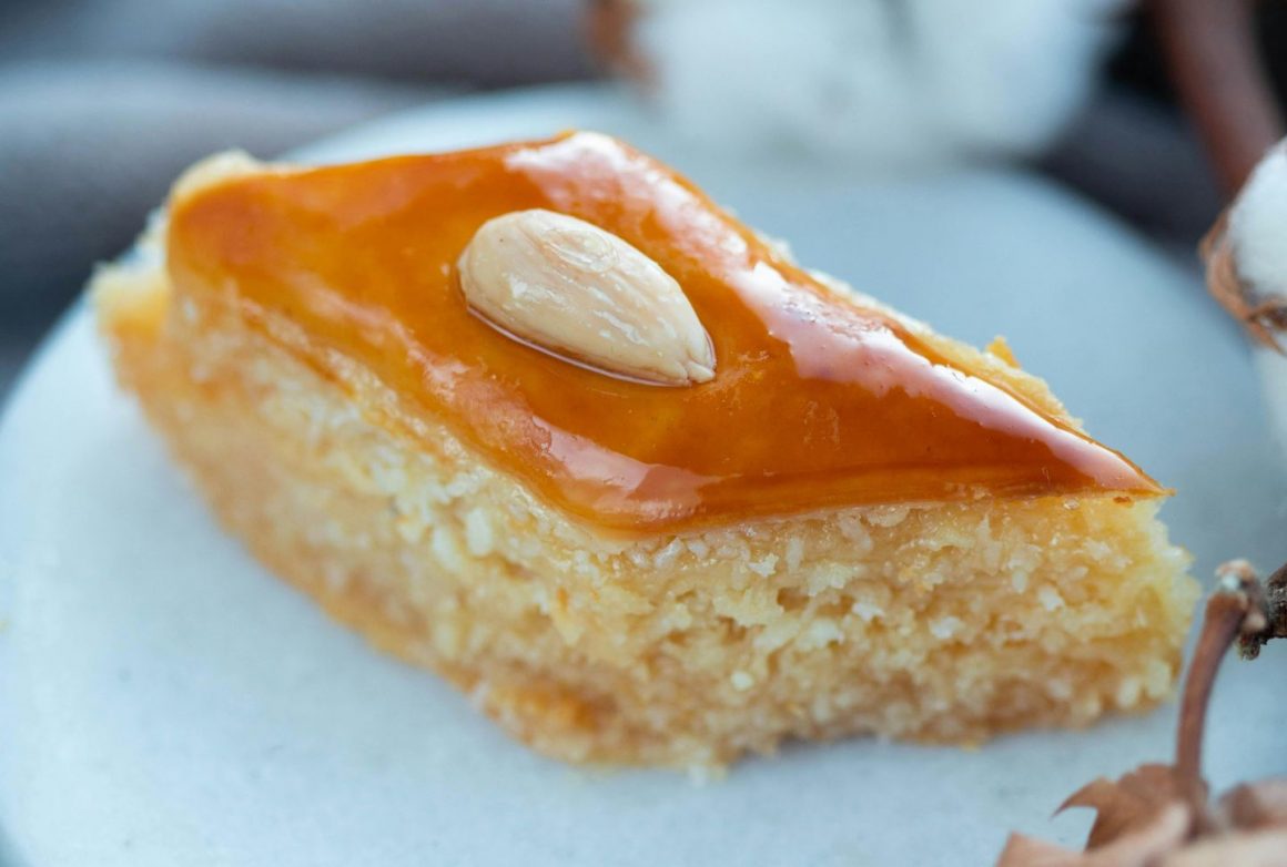 prăjitură sambali cu un sambure de migdala in mijloc taiata in forma de romb, pe o farfurie alba.