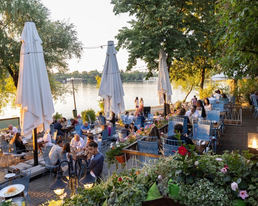 imagine cu oameni la masa pe terasa restaurantului Pescăruș, restaurant pescăresc București