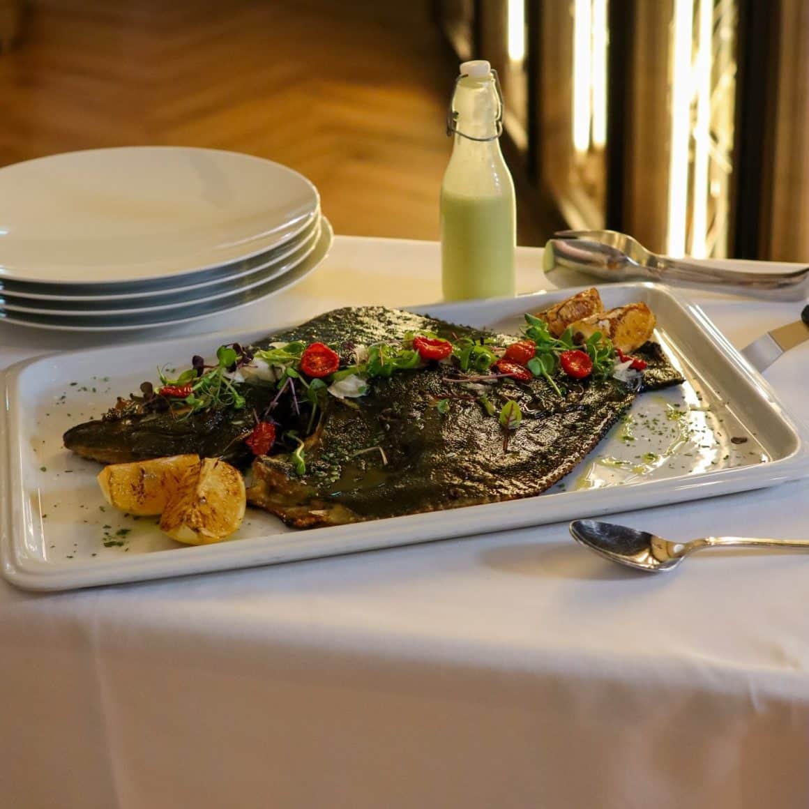 calcan la grătar servit pe tavă, cu lămâie și roșii cherry, Fish House București