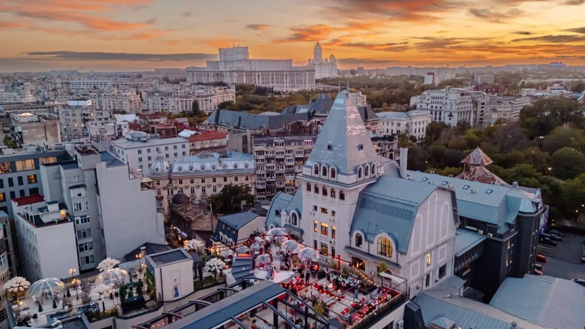 Mai mulți oameni la terasă, la asfințit, la unul din rooftop bars din București. Bartini București