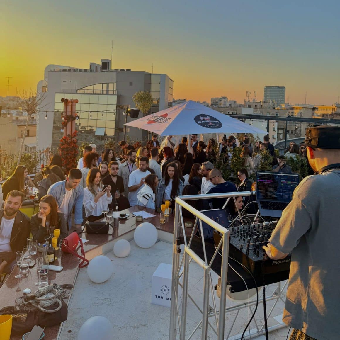 Petrecere vara, pe terasa tip rooftop, cu mai multi oameni care danseaza si un dj booth live
