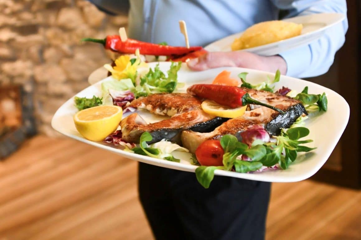 platou cu preparate din peste servit pe farfurie alba cu rosie, salata, lamaie si bobite de coacaze la Popasul Pescarilor, una din cele mai bune cherhanale de la mare