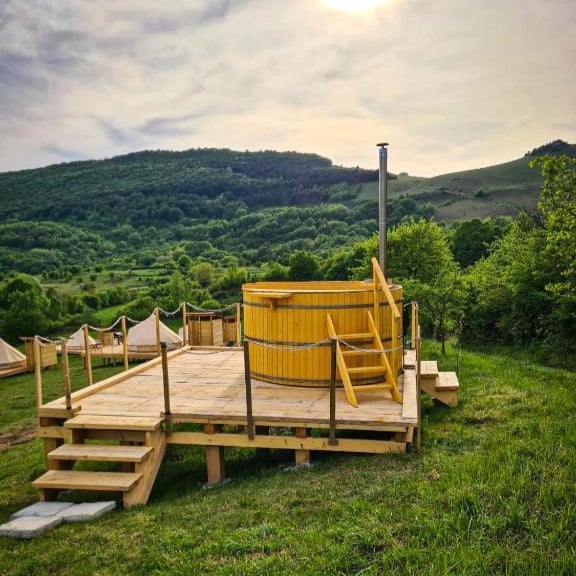 ciubar aplasat pe un podet de lemn, pe iarba, la munte. Cele mai frumoase campinguri din România