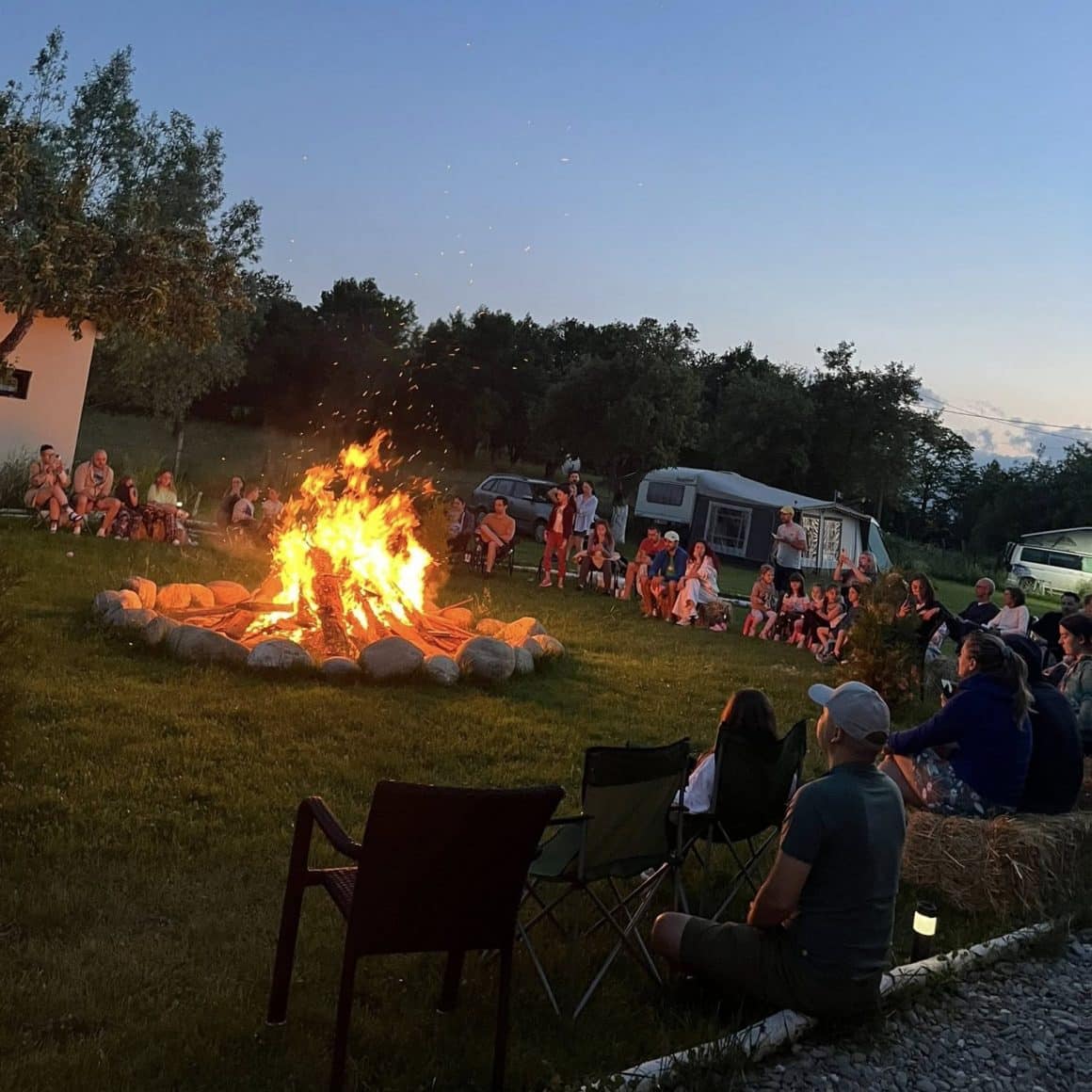 Oameni stransi seara in jurul unui foc de tabara la Heaven Camping Bran