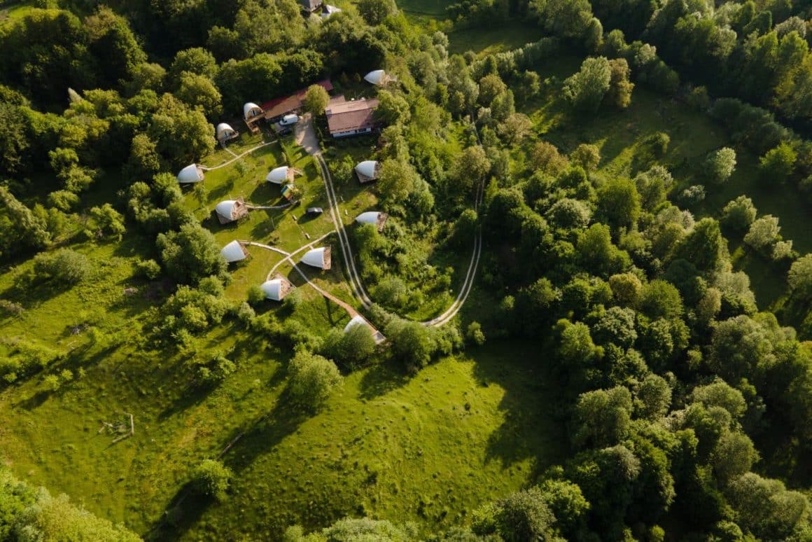 mai multe corturi de glamping răsfirate pe un deal inverzit. Sunrise Glamping Retreat. Cele mai frumoase campinguri din România