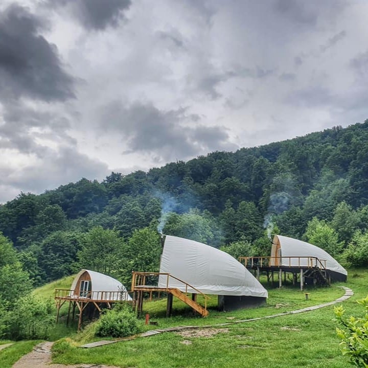 mai multe corturi de glamping răsfirate pe un deal inverzit. Sunrise Glamping Retreat. 