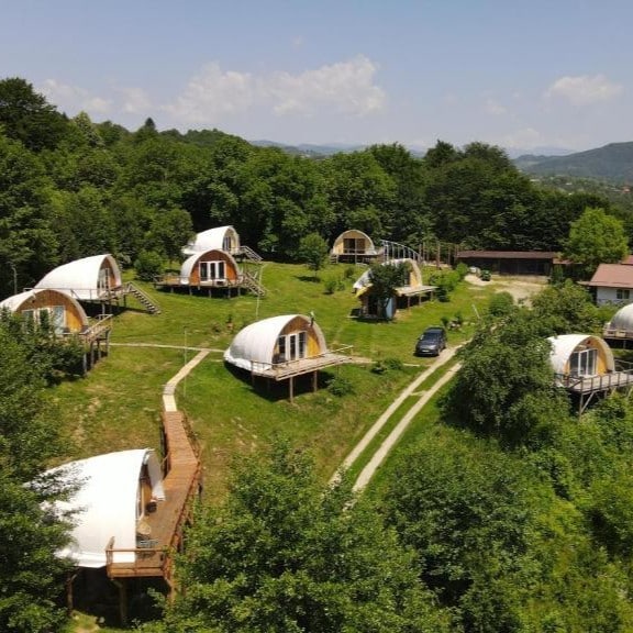 mai multe corturi de glamping răsfirate pe un deal inverzit. Sunrise Glamping Retreat. Cele mai frumoase campinguri din România