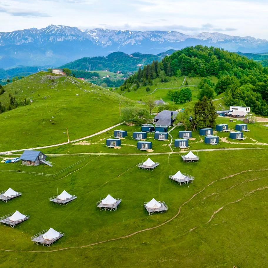 mai multe corturi de glamping răsfirate pe un deal inverzit. Ursa Mică. Cele mai frumoase campinguri din România