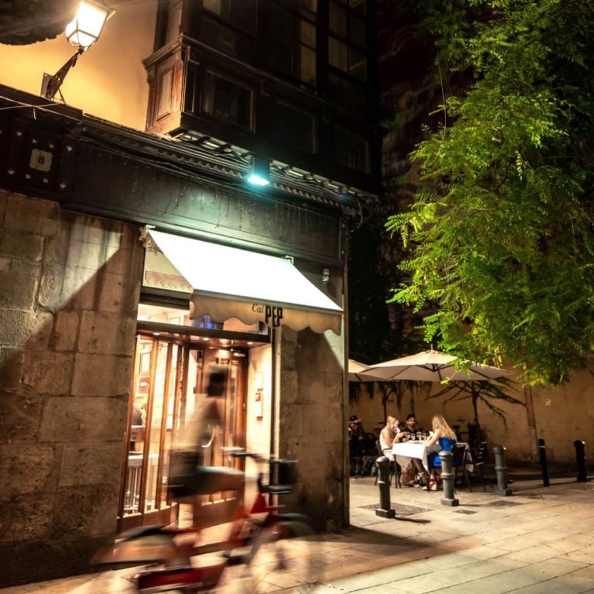 Fațada discretă a restaurantului Cal Pep, luminată seara, loc cunoscut pentru tapas proaspete și atmosferă locală.