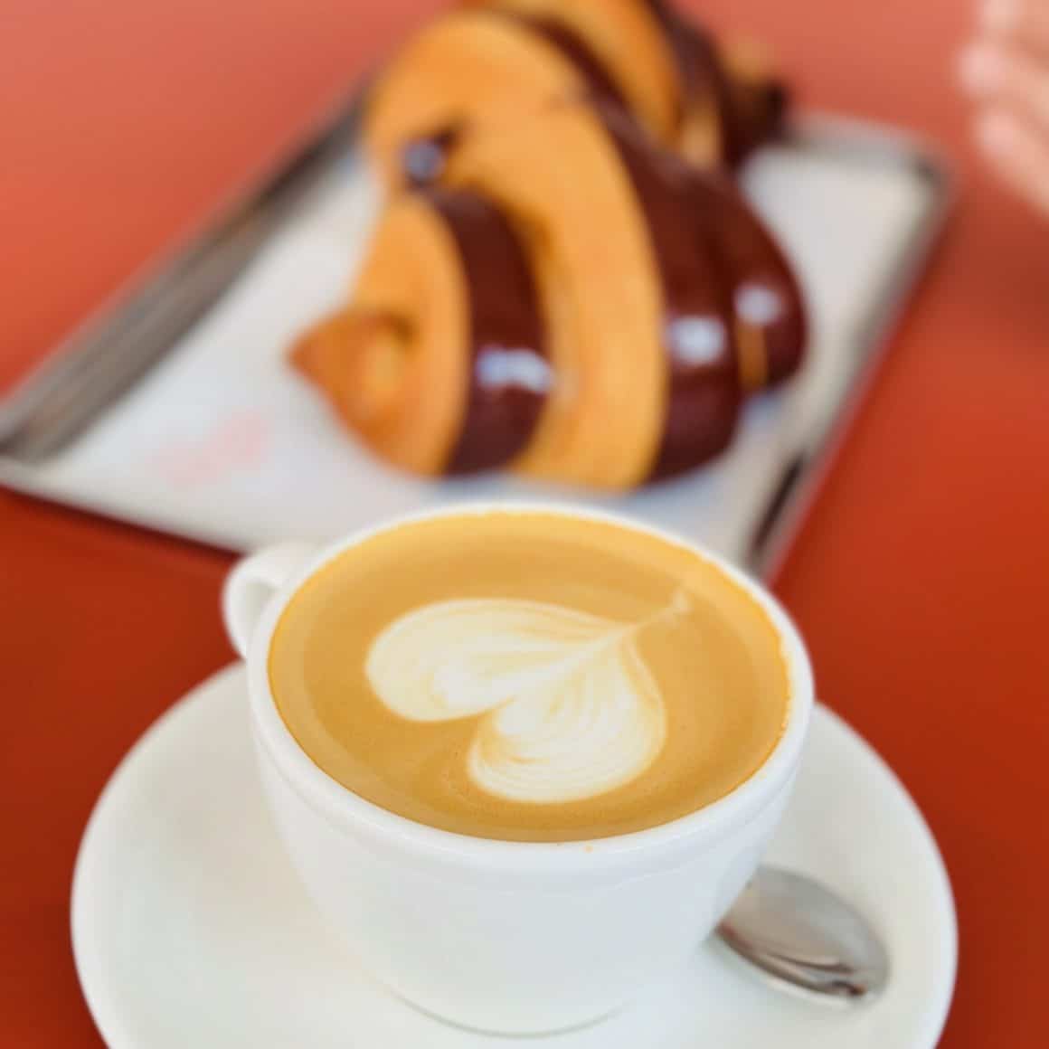 prim plan cu o cafea si in fundal groissant de la Gluten Glory Bucureti