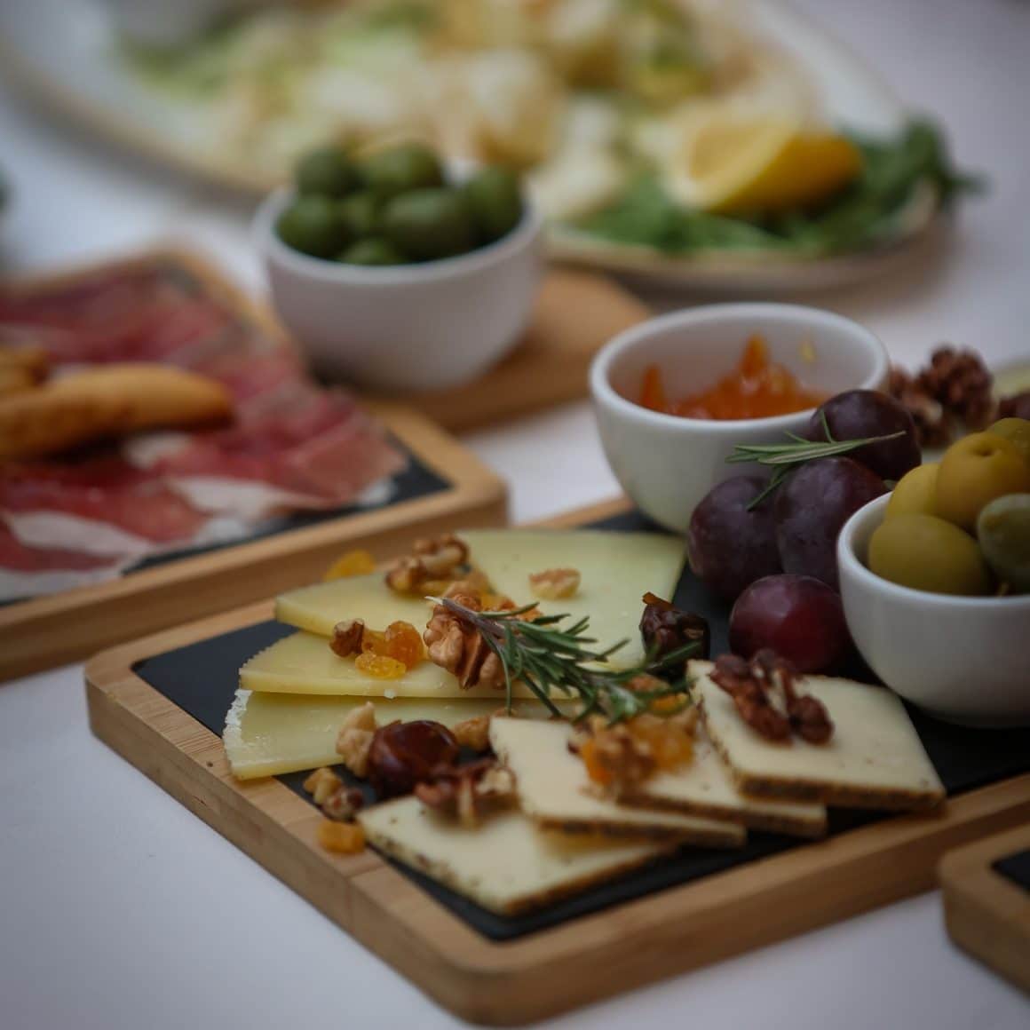 Platou cu tapas în București – brânzeturi cu nuci și fructe, măsline și struguri, servite pe tăvi de lemn