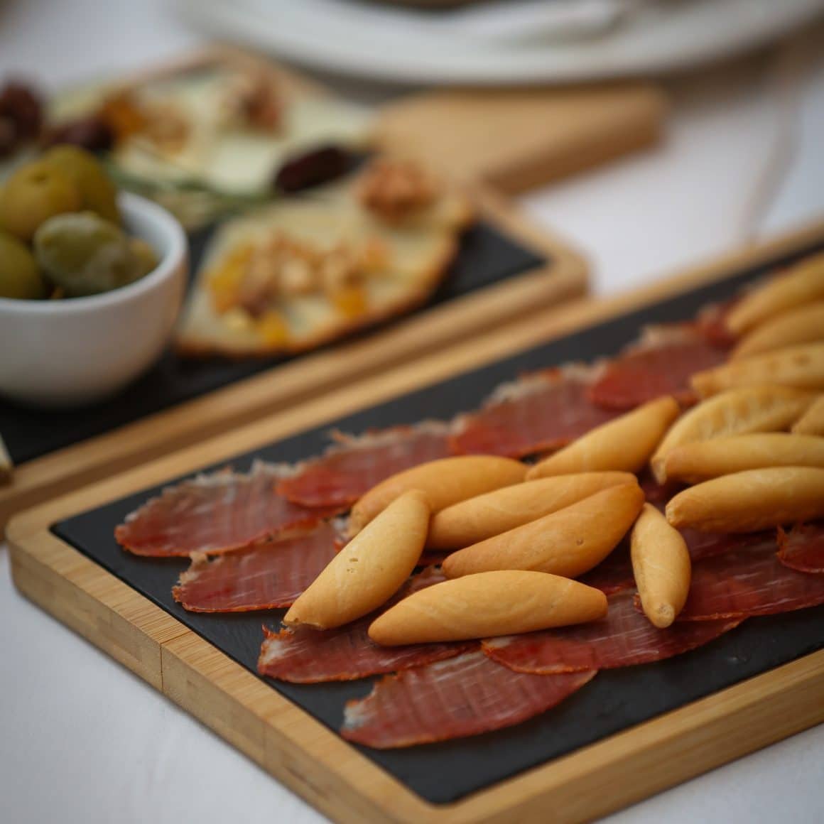 jamón ibérico și pâinici crocante, servite pe platou într-un restaurant din București