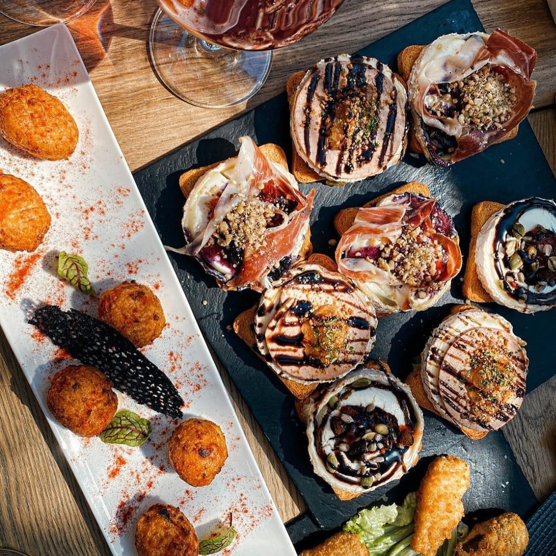 Tapas în București – bruschete cu prosciutto, brânză și reducție balsamică, alături de croquetas.