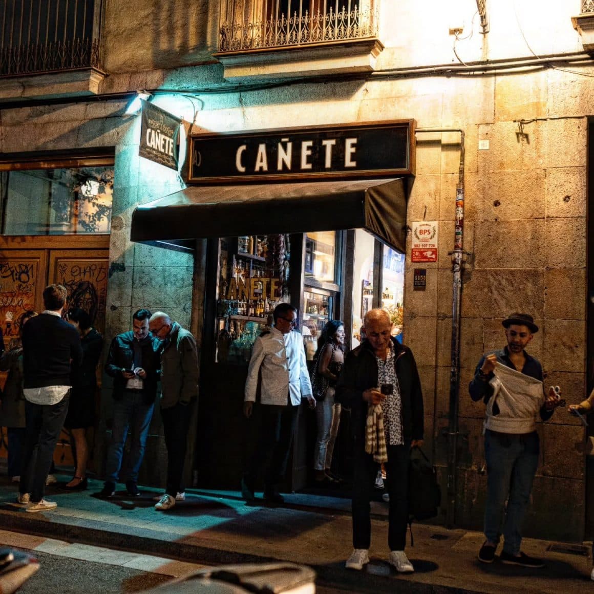 Oameni adunați în fața Bar Cañete, pregătiți să prindă un loc la bar pentru o seară lungă de tapas. Restaurante din Barcelona