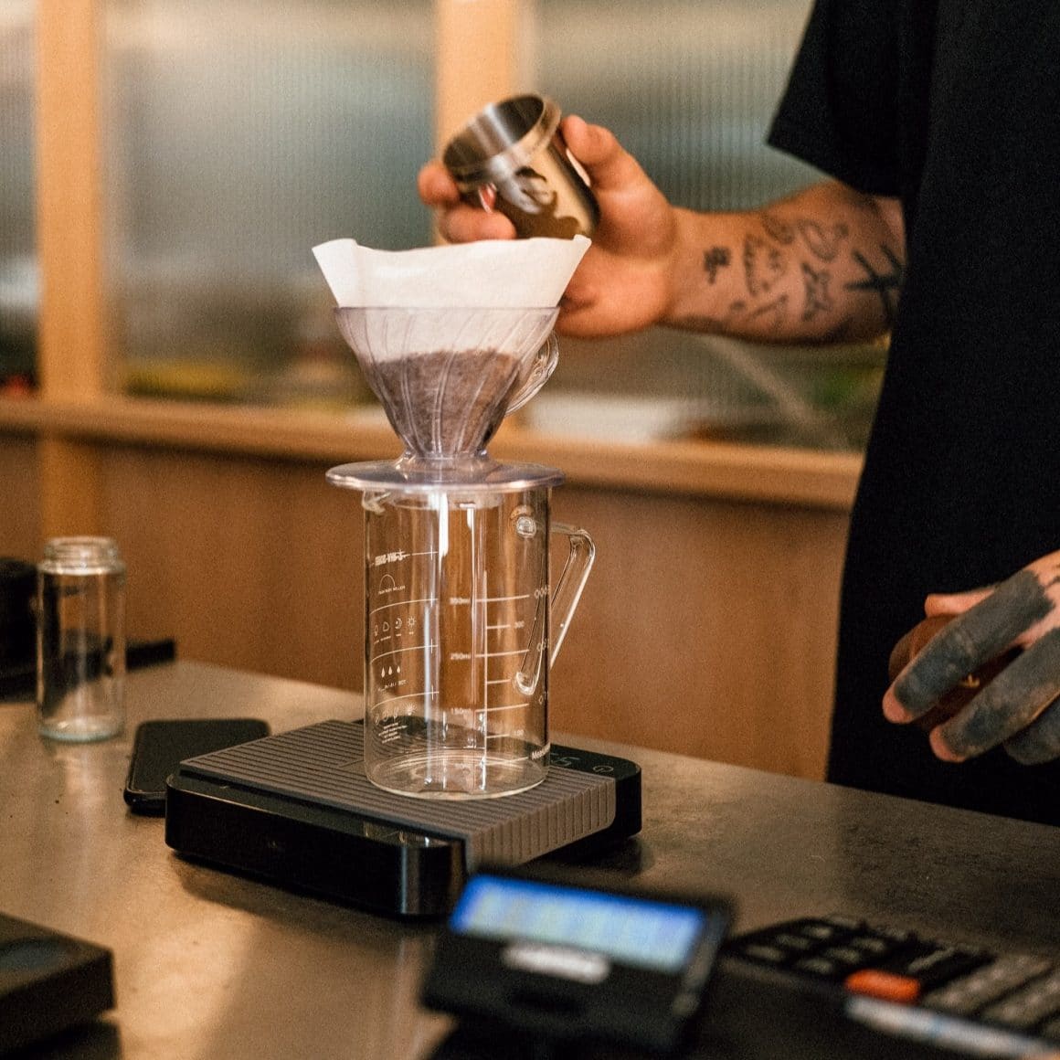 Barista pregătește cafea de specialitate la filtru, folosind metode manuale precum V60, pentru o experiență autentică și aromă intensă.