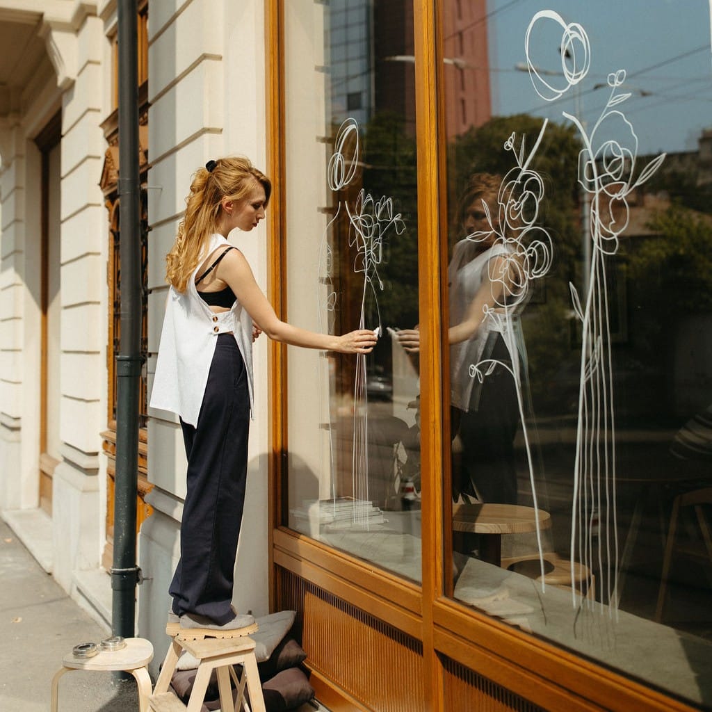 Tanara artista deseneaza geamurile mari de la strada la Sip Coffee & Wine Bar