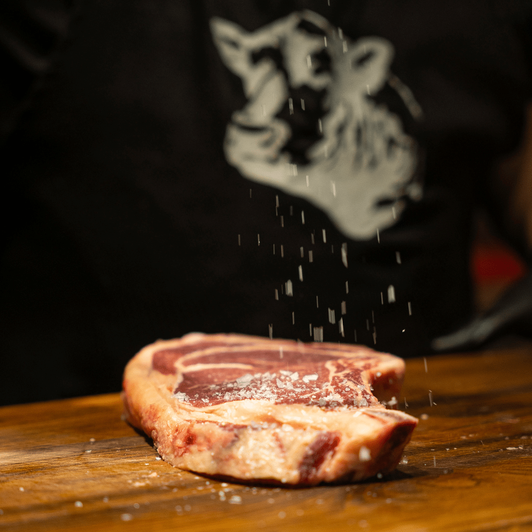 close up cu o felie de carne d evita cruda, marmorata, peste care se presara sare