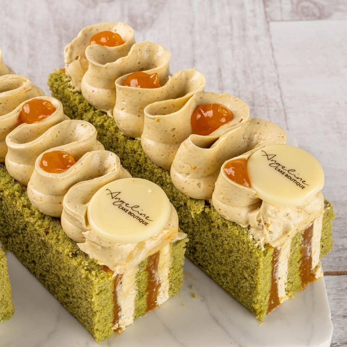 Matcha Layer, o prăjitură cu blat de matcha și fistic, strat de jeleu de mango, portocală și fructul pasiunii, plus un ganache lejer de fistic cu citrice