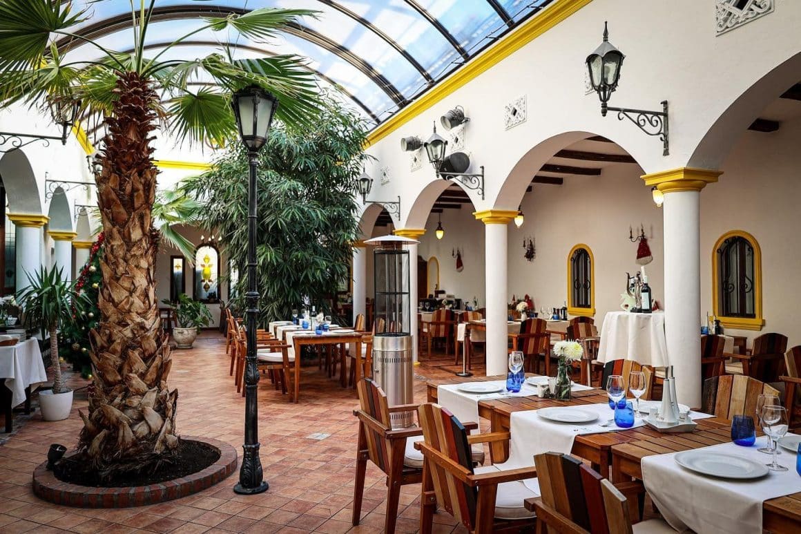 Interior Casa España, restaurant de tapas în București, cu grădină acoperită, palmieri și mese pregătite pentru cină