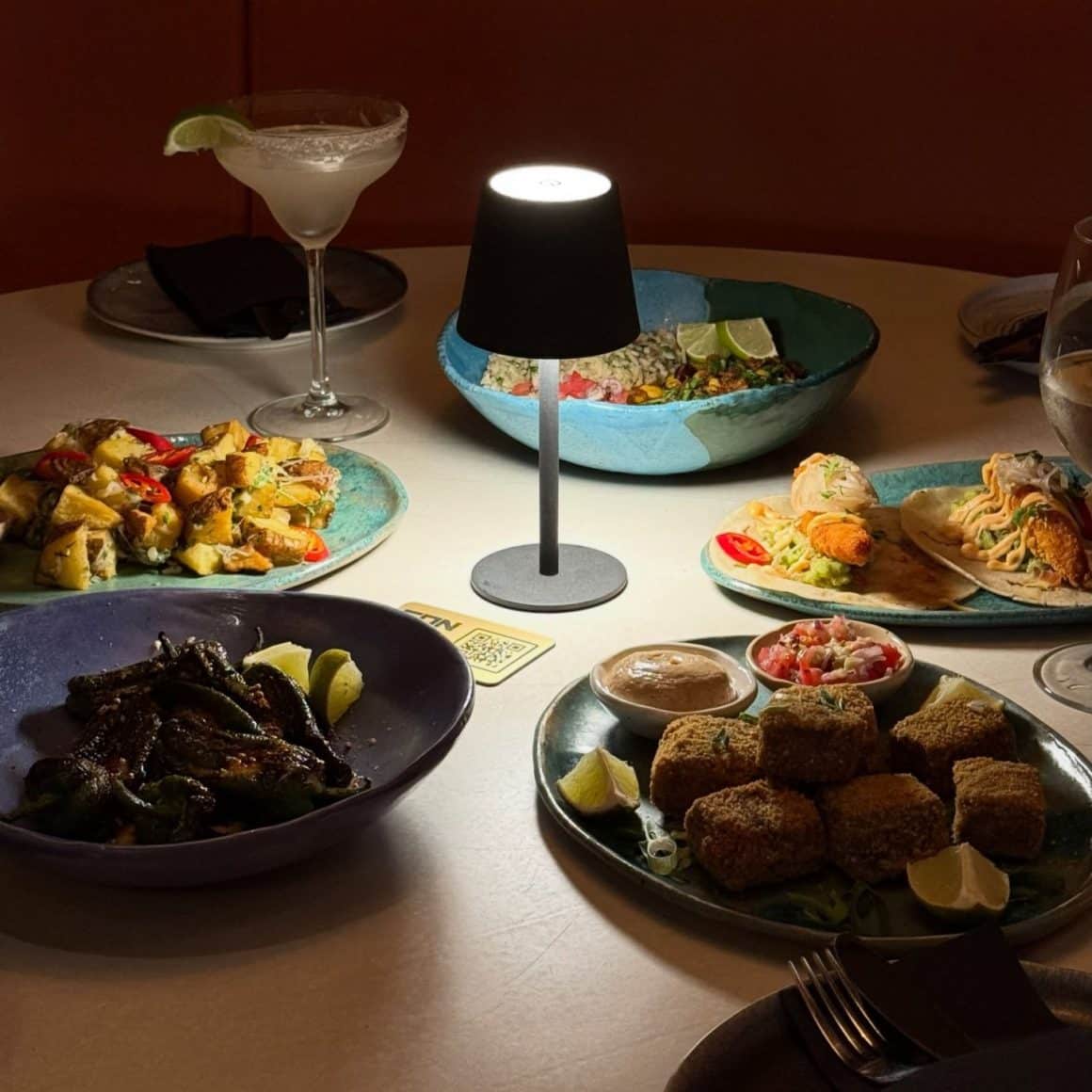 Mai multe sharing plates asezate pe masa, la lumina unei lampi ambientale, a Condesa
