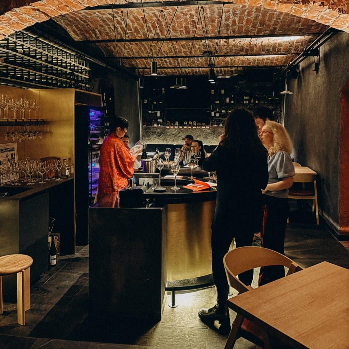 un somelier serveste oaspetii cu vin intr-un wine bar