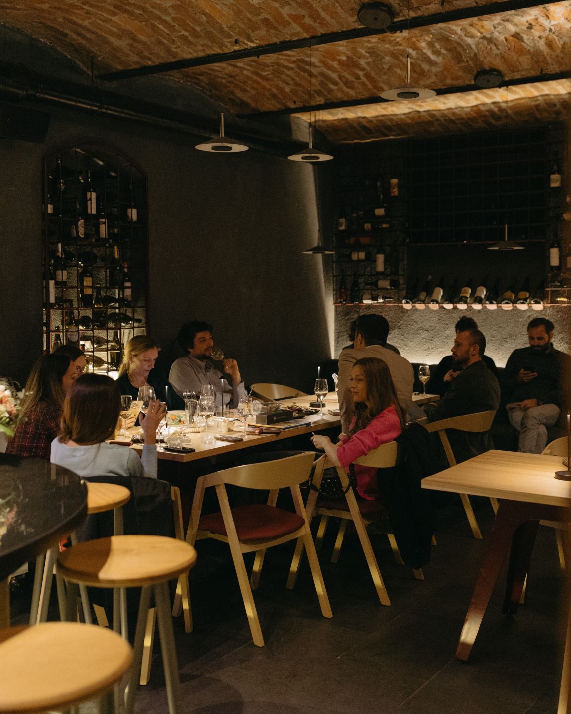 Mai multi oameni iau cina la un pahar de vin, in wine bar-ul de la subsolul Sip Coffee & Wine Bar