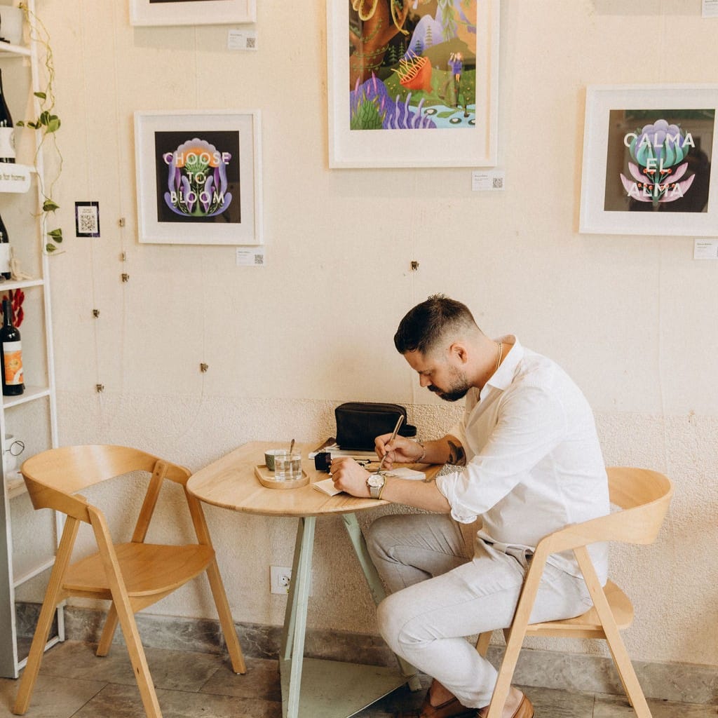 un barbat lucreaza la masa intr- cafenea