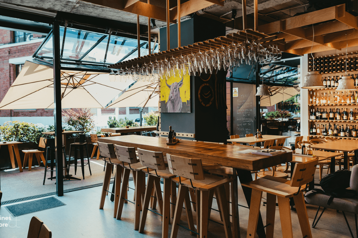 Interior VINO Bubbles & Tapas București, bar modern cu mese înalte, vinuri expuse și atmosferă relaxată.