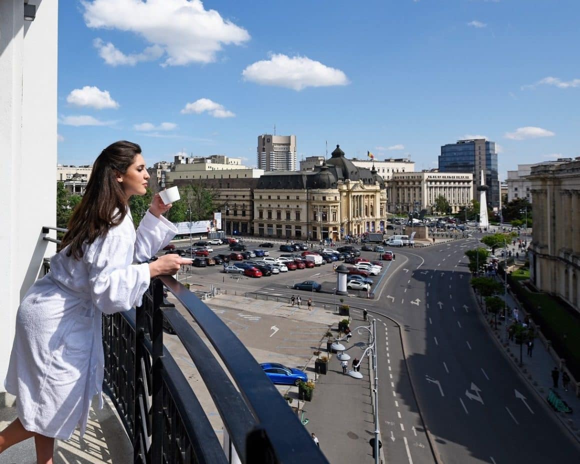 Femeie savureaza o cafea pe balconul hotelului  hotel InterContinental Athénée Palace, cu privire catre Calea Victoriei