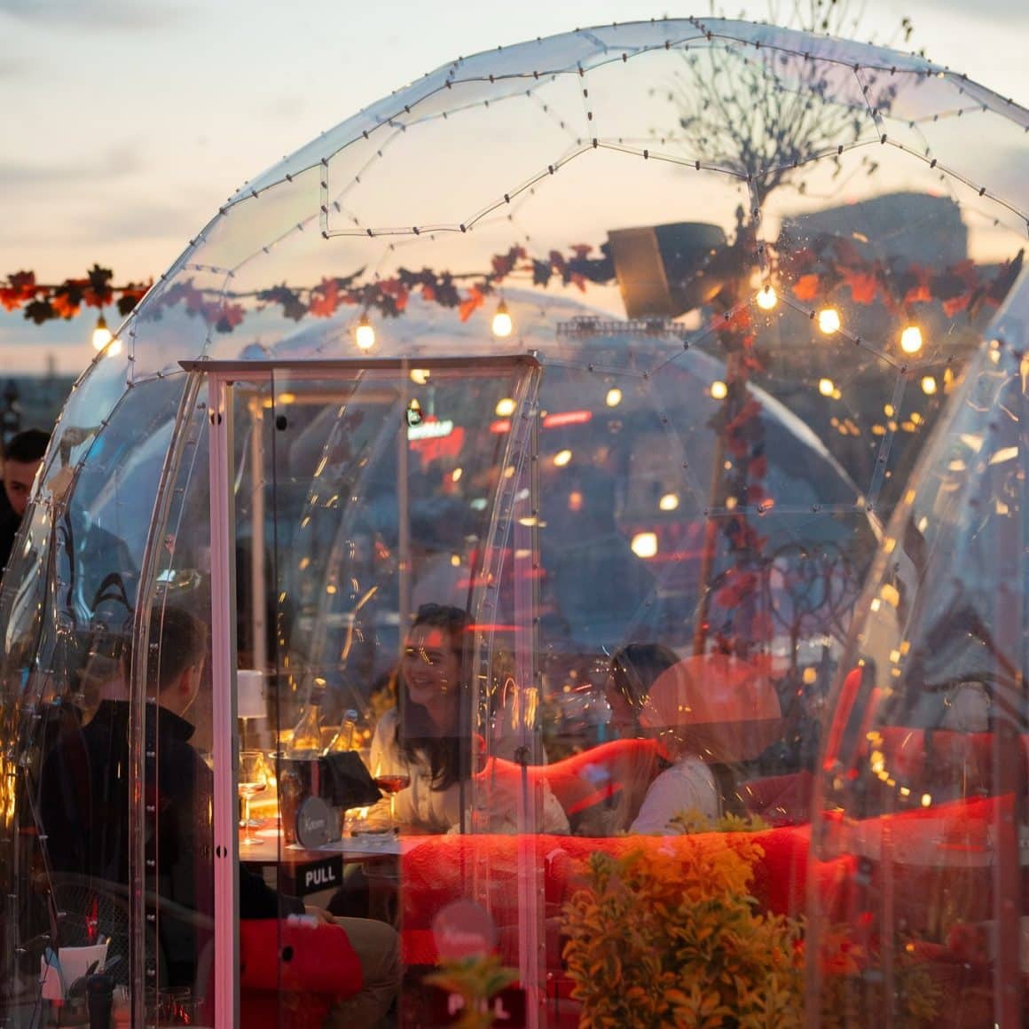 oameni iau masa in igluu pe terasa la Bartini Rooftop București