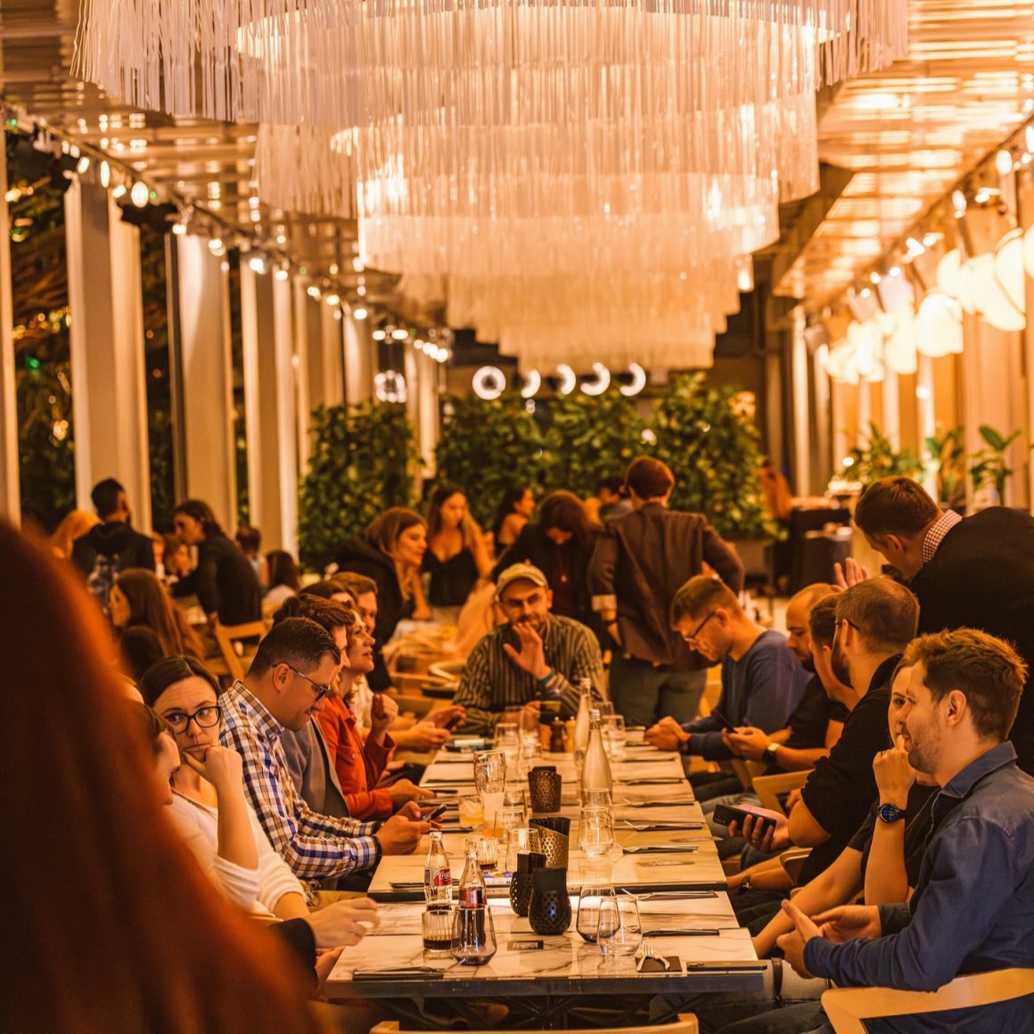 Mai multi oameni la o masa intinsă la petrecerea de Crăciun a firmei la Linea Closer to the Moon