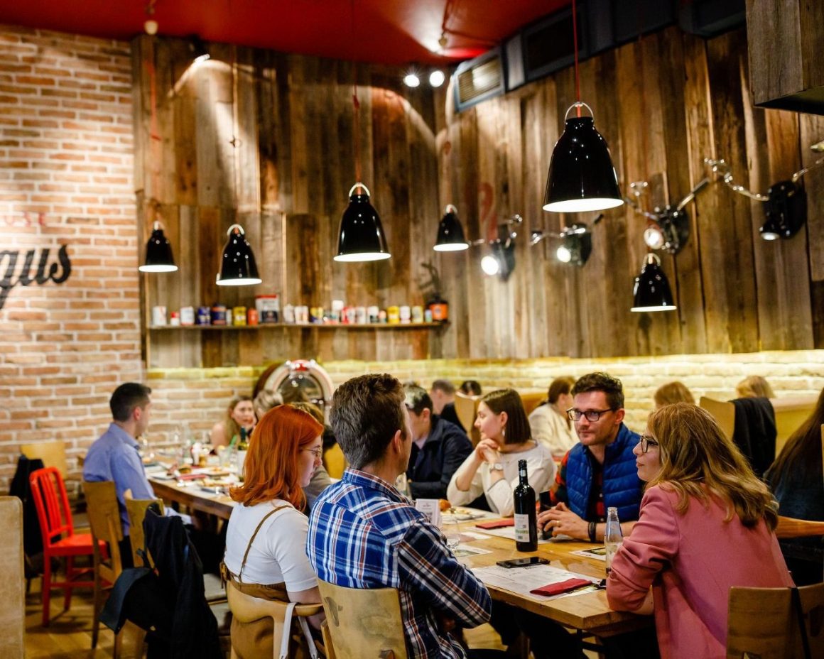 Mai multi oameni la o masa intinsă la petrecerea de Crăciun a firmei la red Angus