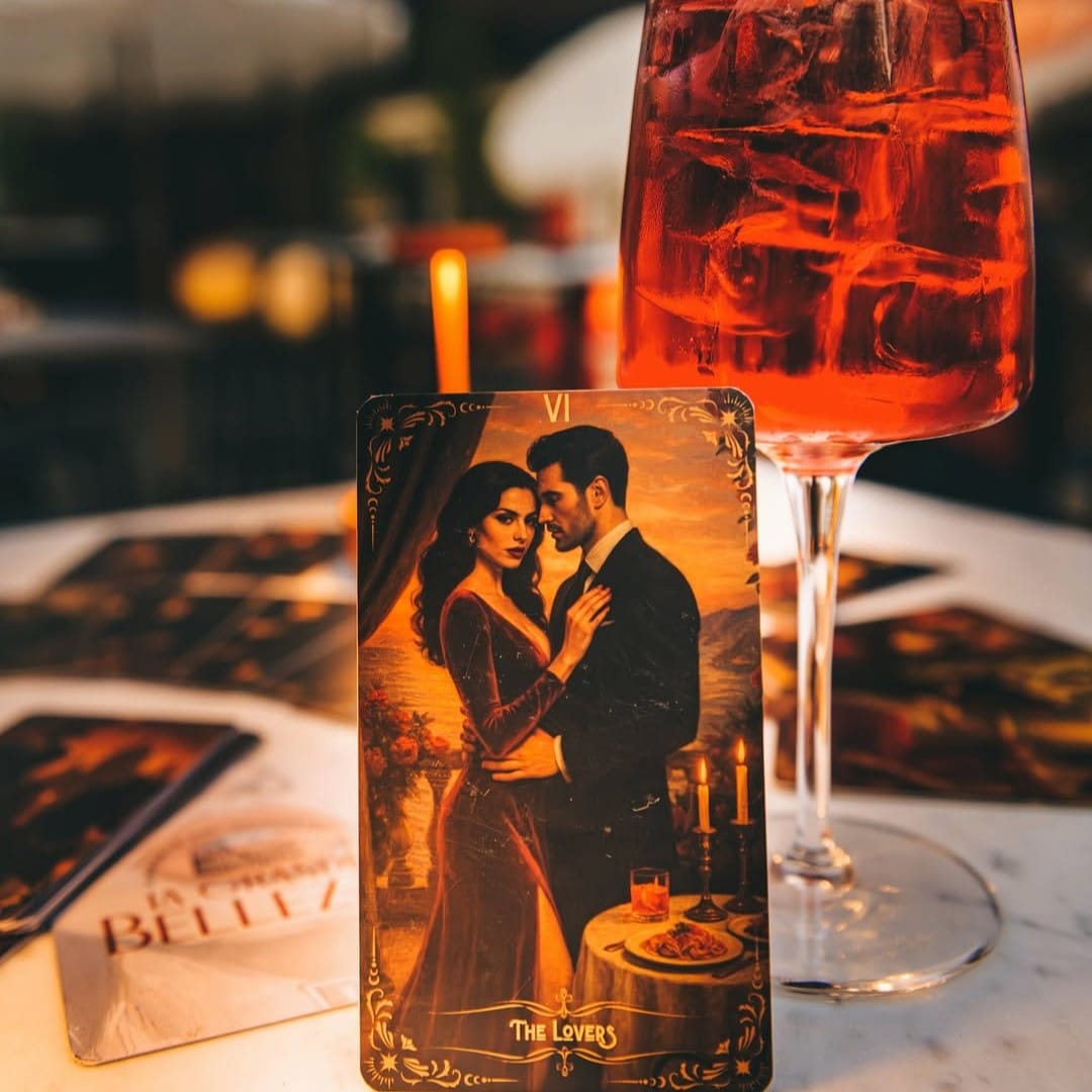 carte de tarot cu un cuplu de indragostiti sprijinita de un pahar de cocktail