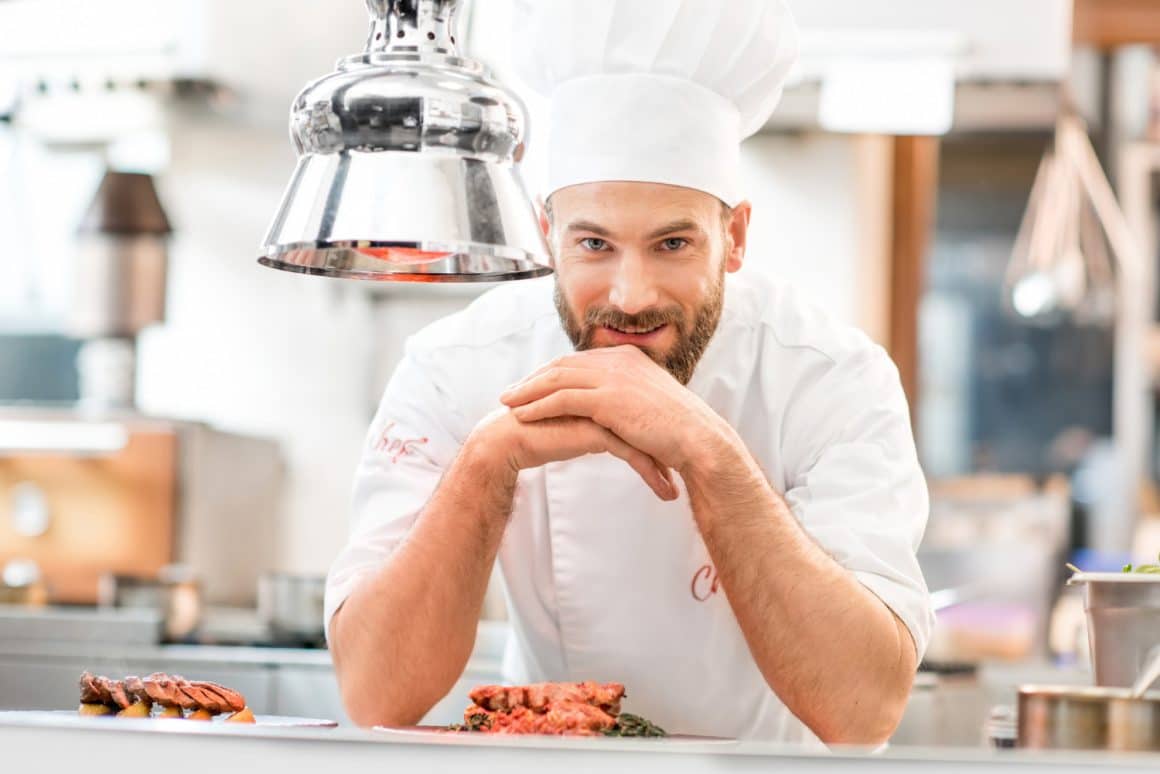 Prim plan cu un chef imbracat in tunica si cu boneta. Imagine reprezentativă pentru bucătari mediatizați și faimoși