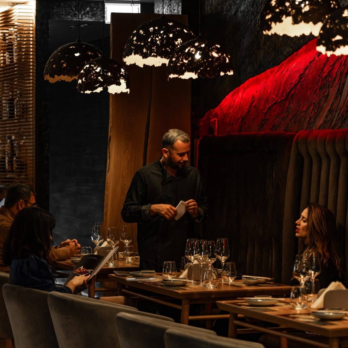 Ospătar servește la masă două prietene ieșite la cină la Yoshi Sushi din București